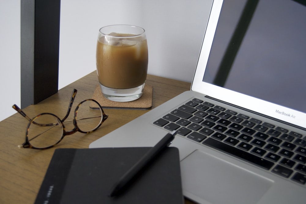 macbook air beside clear glass mug