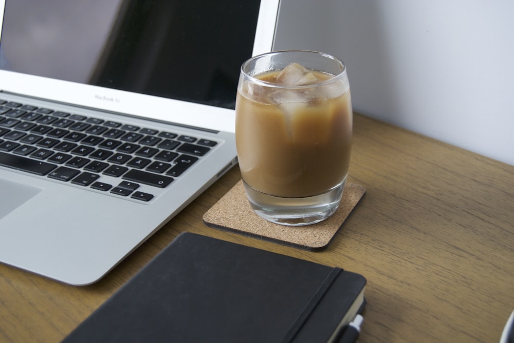 clear drinking glass with brown liquid on brown wooden table