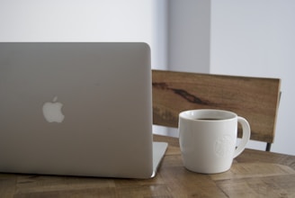 A sleek laptop on a minimalist desk with a stylish coffee cup beside it.