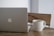 A close-up of a sleek laptop on a wooden desk with a coffee cup beside it.