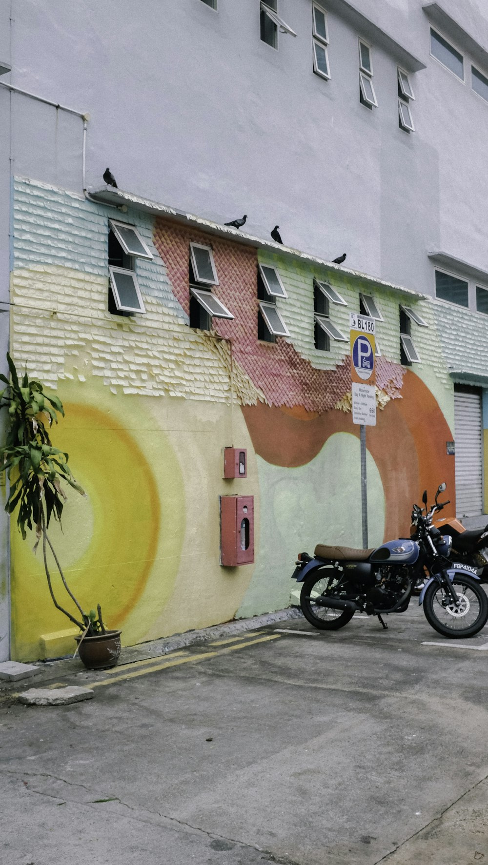 black motorcycle parked beside red yellow and blue concrete building during daytime
