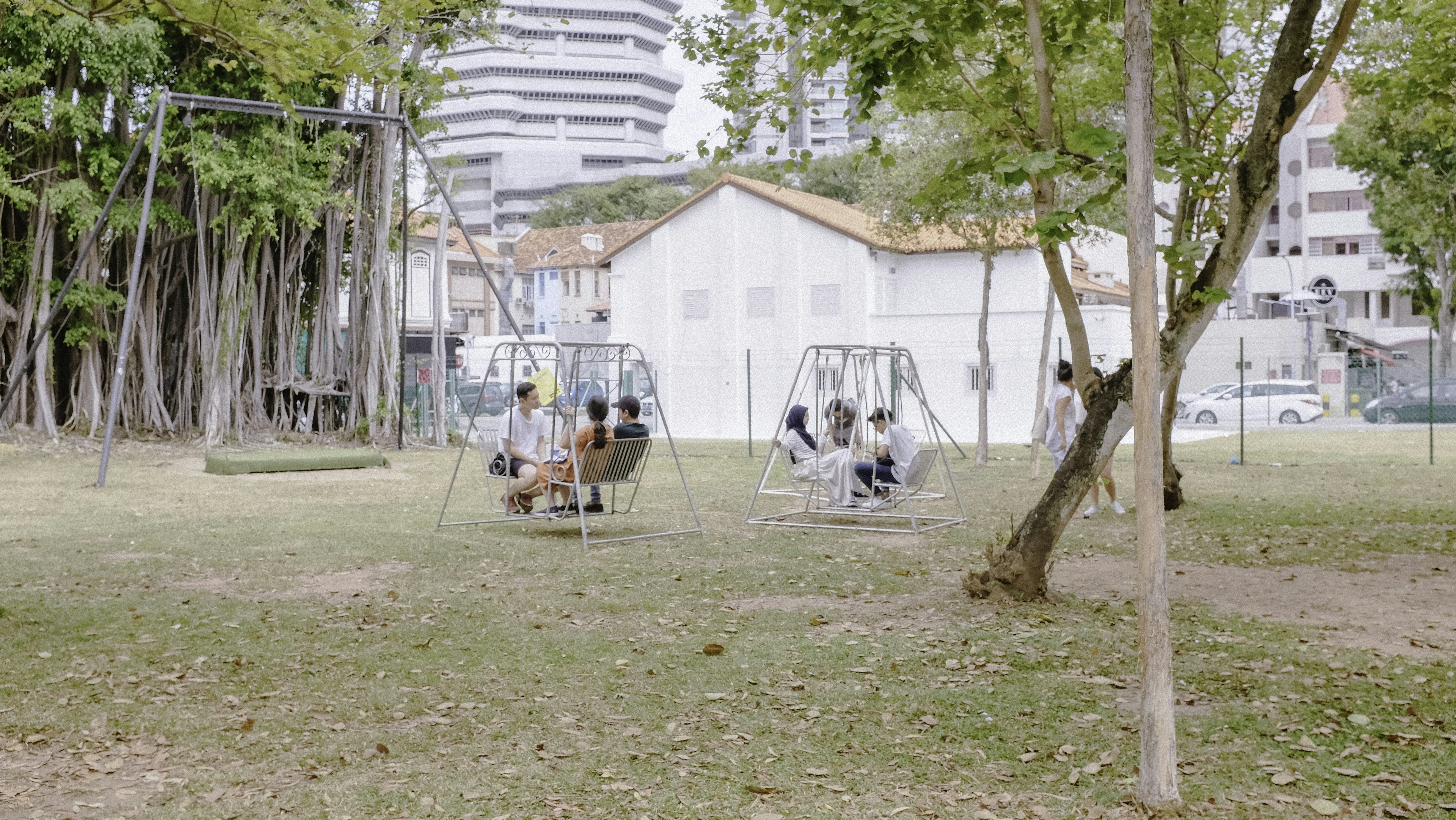 people sitting on chairs near white wooden house during daytime