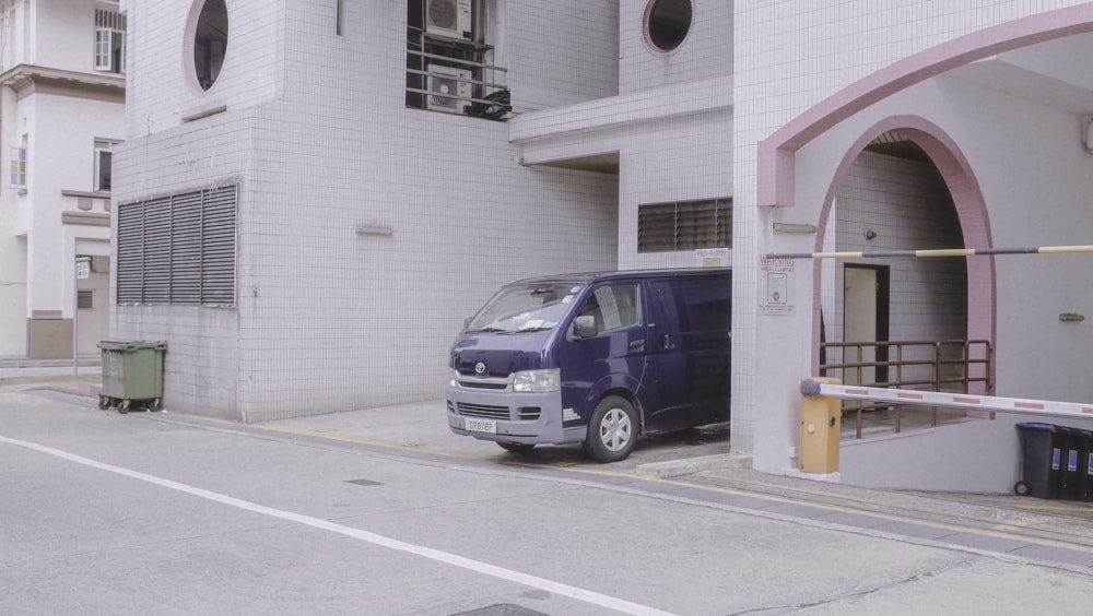 white and blue van parked beside white building