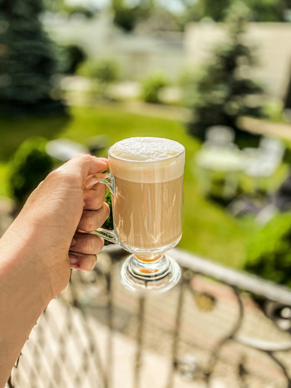 person holding clear glass mug with brown liquid