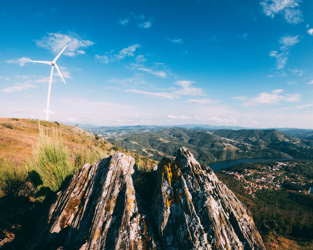 white wind turbine on brown and green mountain under blue sky during daytime