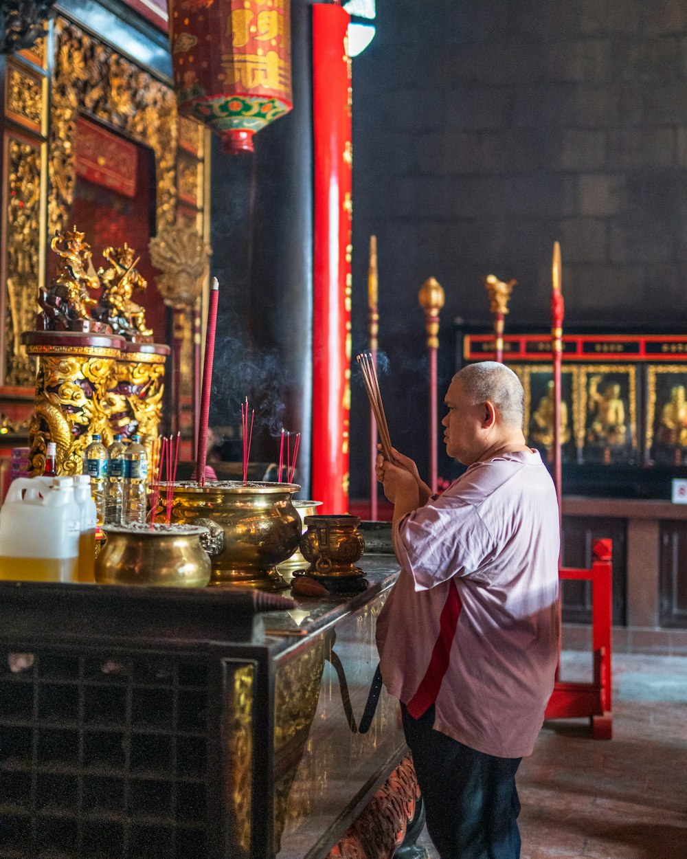 man in white dress shirt standing near gold buddha figurine