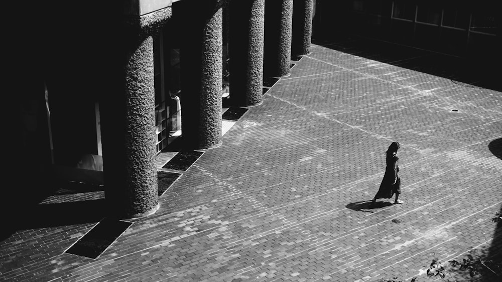 grayscale photo of person walking on sidewalk