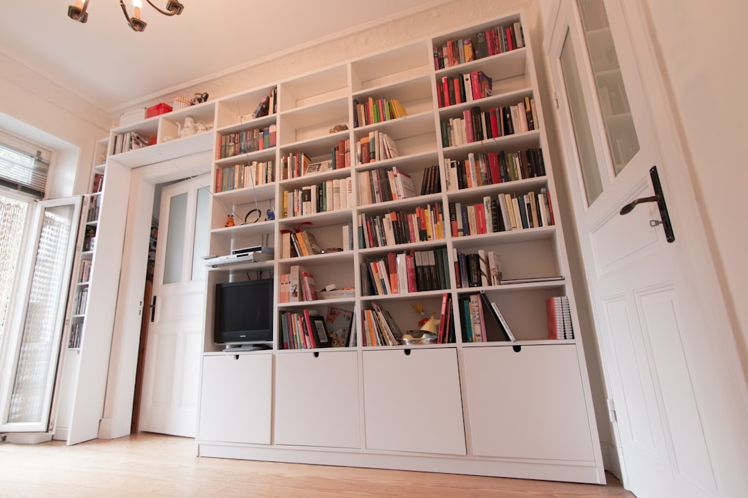 white wooden book shelves with books, Modern wall shelf with a cut-out for the door.