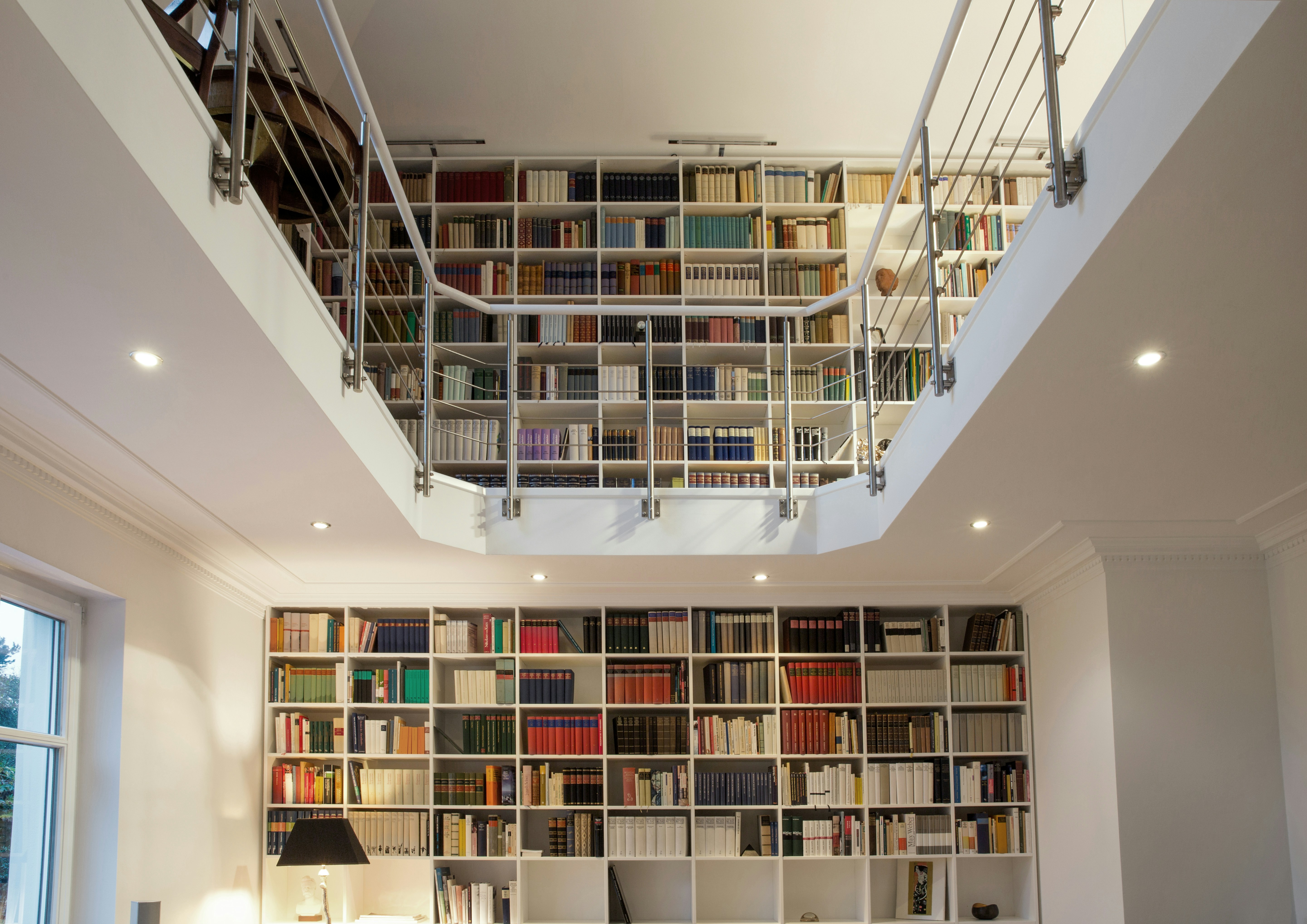 Two storey library with white custom made shelves.