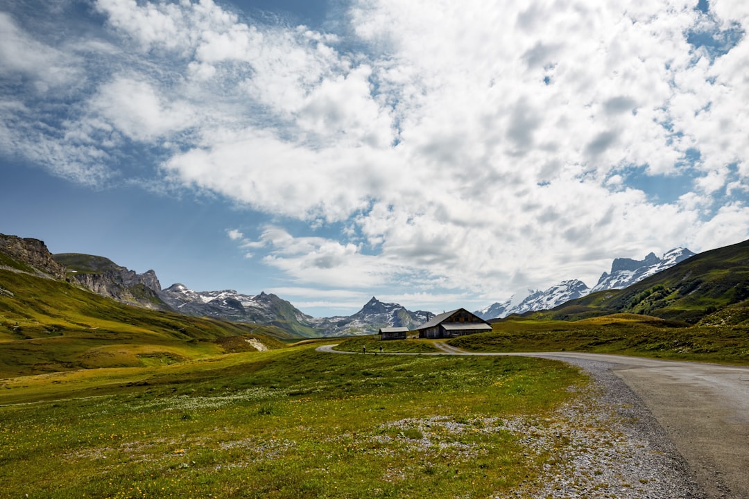 green grass field near mountain under cloudy sky during daytime