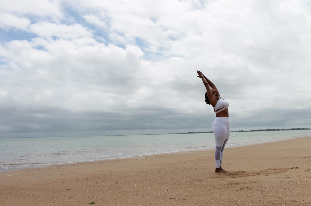 woman in white long sleeve shirt and white pants standing on beach shore during daytime