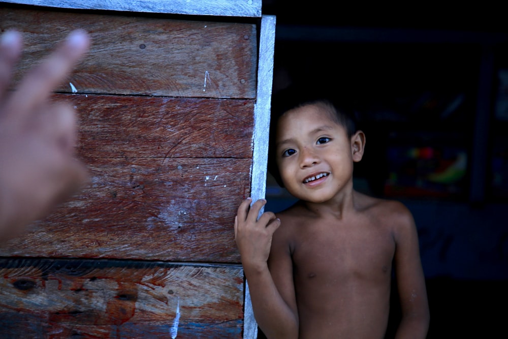 topless boy holding brown wooden frame