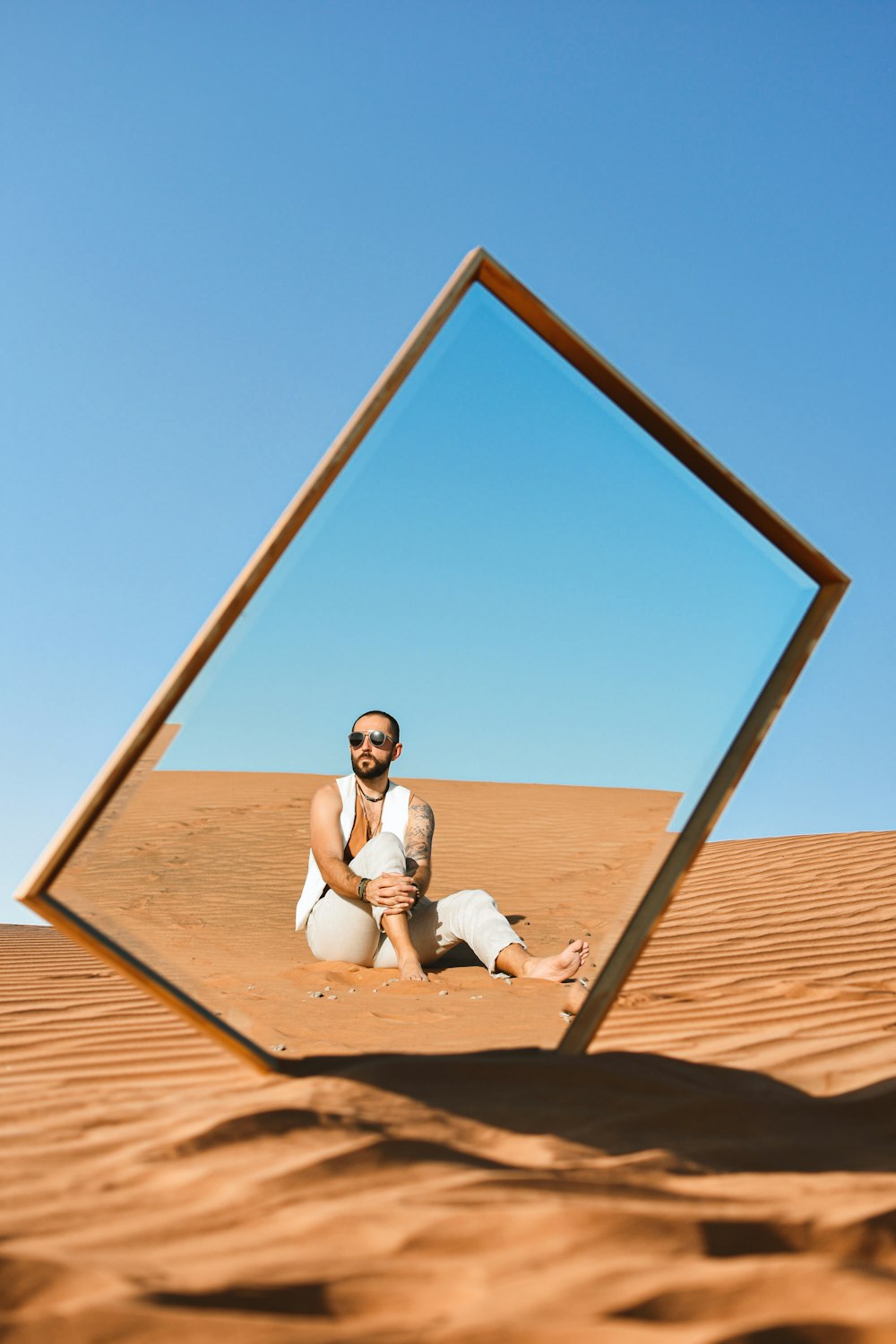 man and woman sitting on brown sand under blue sky during daytime