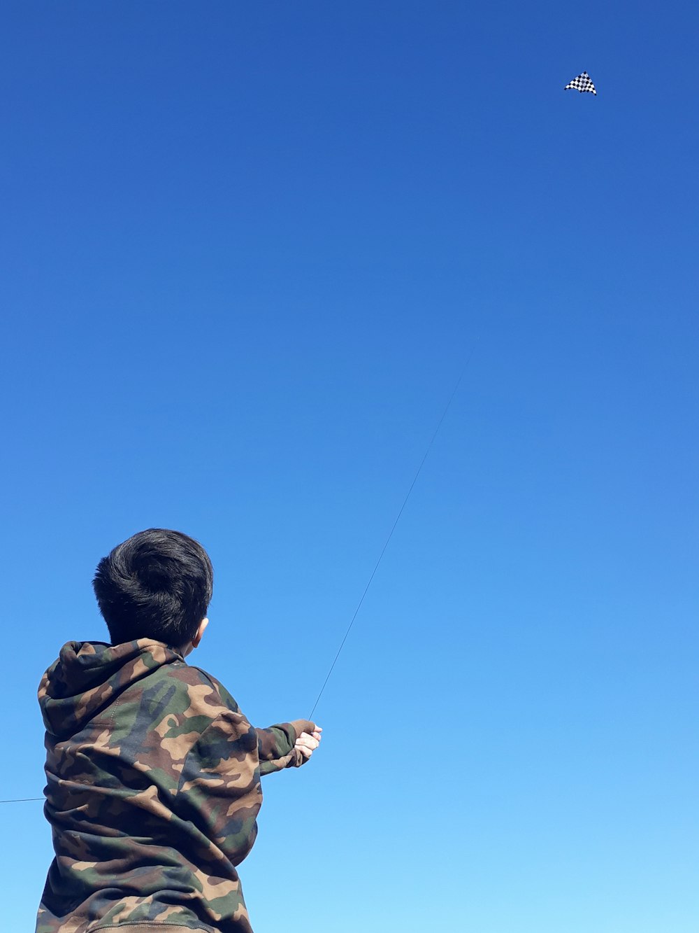 man in black and brown camouflage hoodie holding black fishing rod under blue sky during daytime