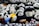 A collection of panda plush toys, some with unique designs and colorful details like blue and yellow clothing. The toys are arranged closely together, creating a playful and cozy atmosphere.