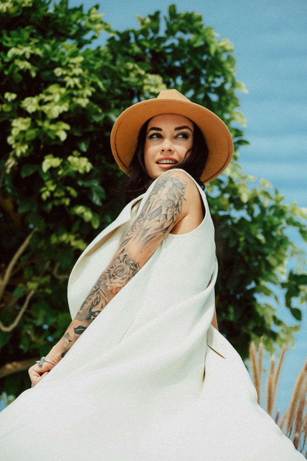 woman in white sleeveless dress wearing brown sun hat