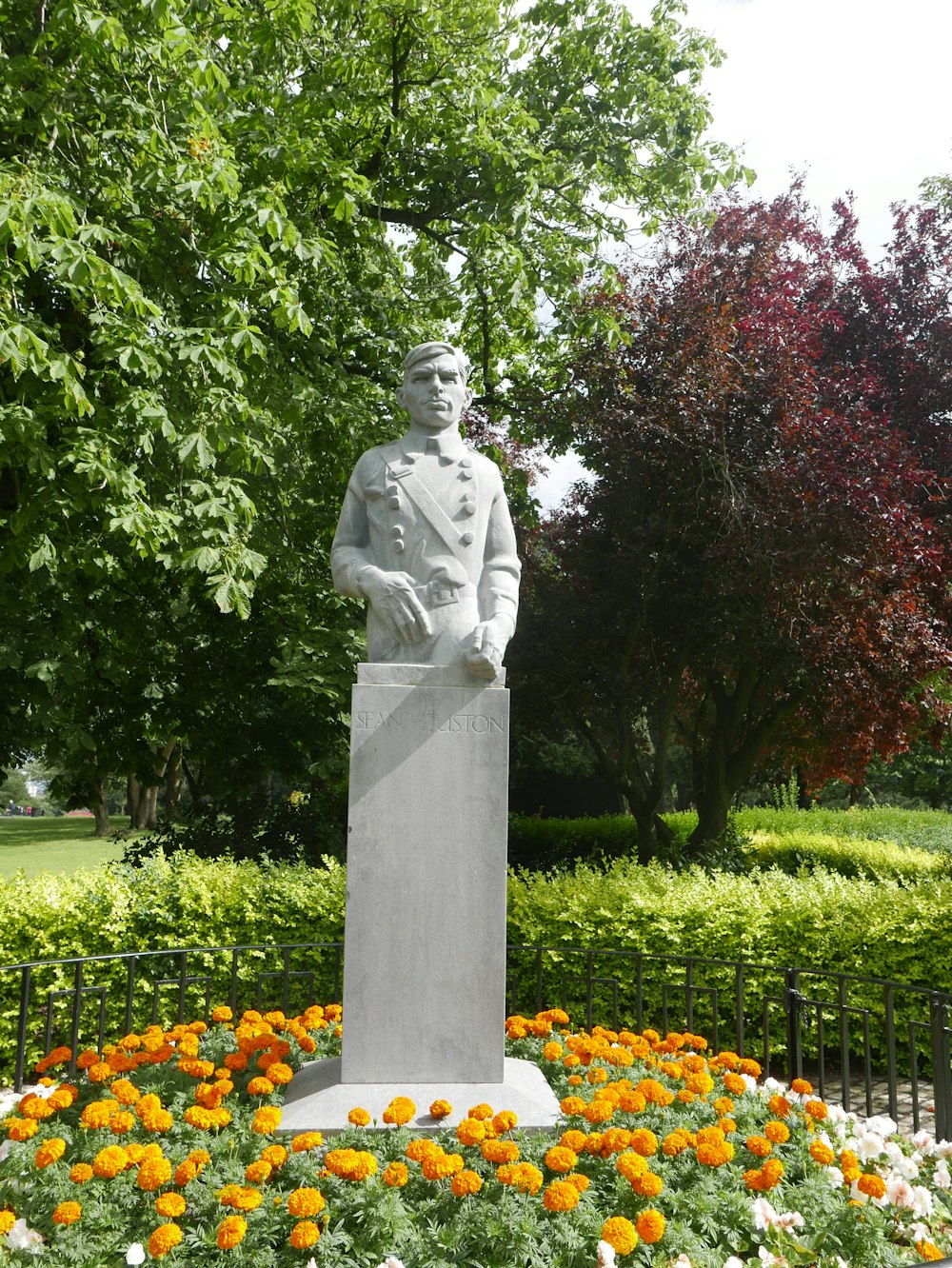 Mann in Gewand Statue in der Nähe von grünen Bäumen während des Tages
