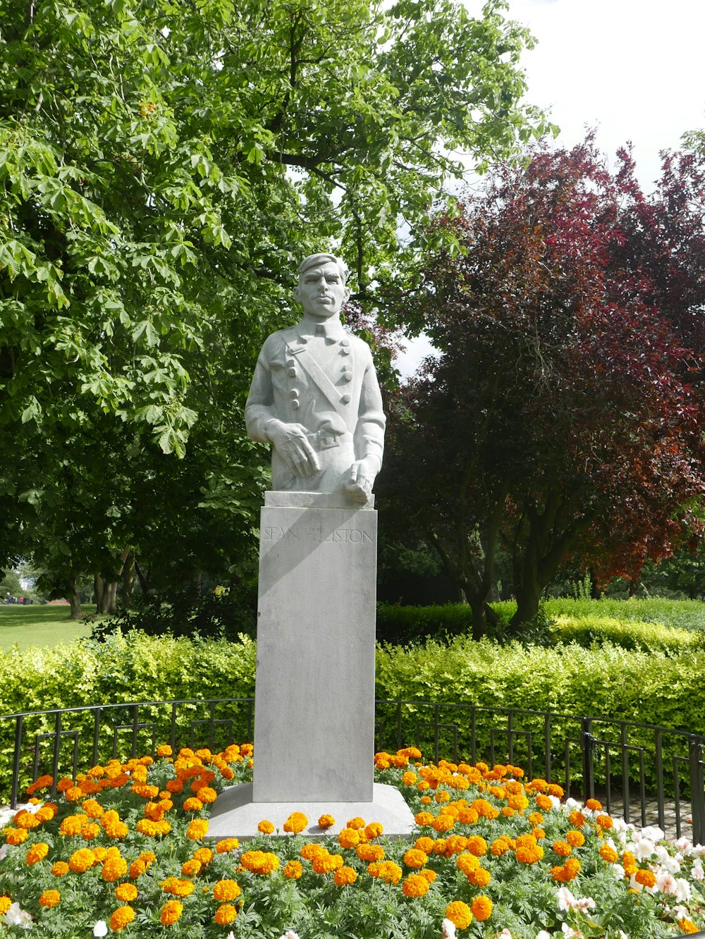 Statue d’homme en robe près d’arbres verts pendant la journée