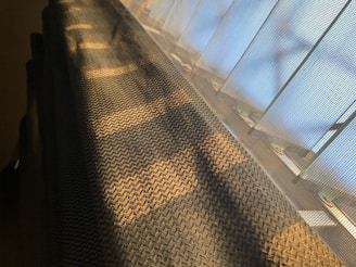 Woven fabric casting shadows with light filtering through a mesh-like surface, creating a pattern of light and shadow in a warm glow.