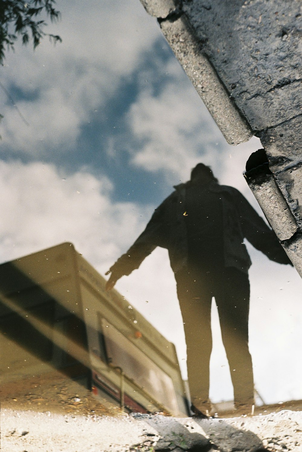 灰色のコンクリートの壁の上に立つ黒いジャケットの男