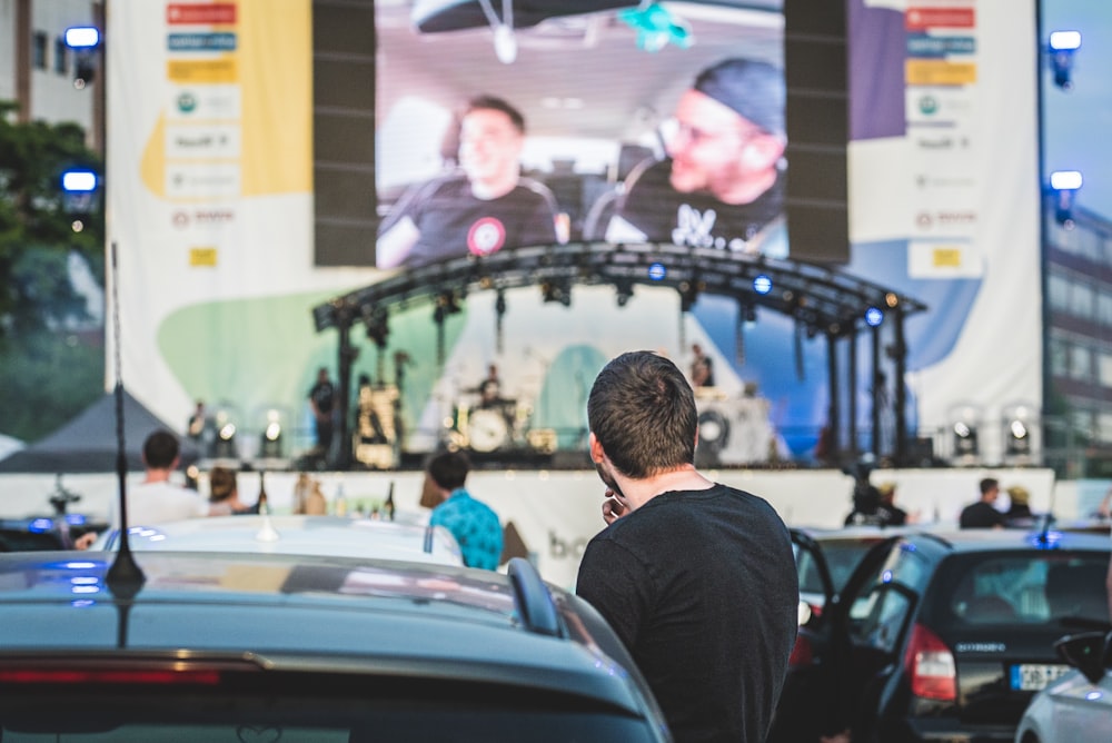 man in black shirt standing near cars during nighttime