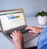 person using macbook air on white table