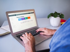 person using macbook air on white table
