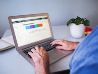person using macbook air on white table