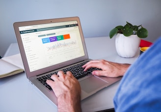 person using macbook air on white table