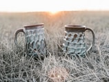 Finished ceramic mugs drying in natural sunlight on a rustic table.