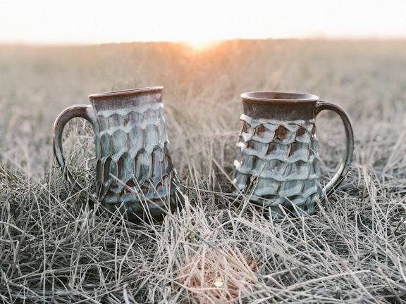 Finished ceramic mugs drying in natural sunlight on a rustic table.