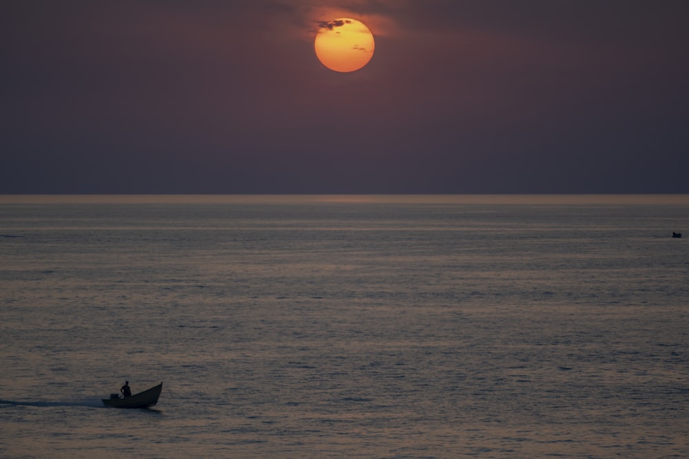 silhouette of boat on sea during sunset