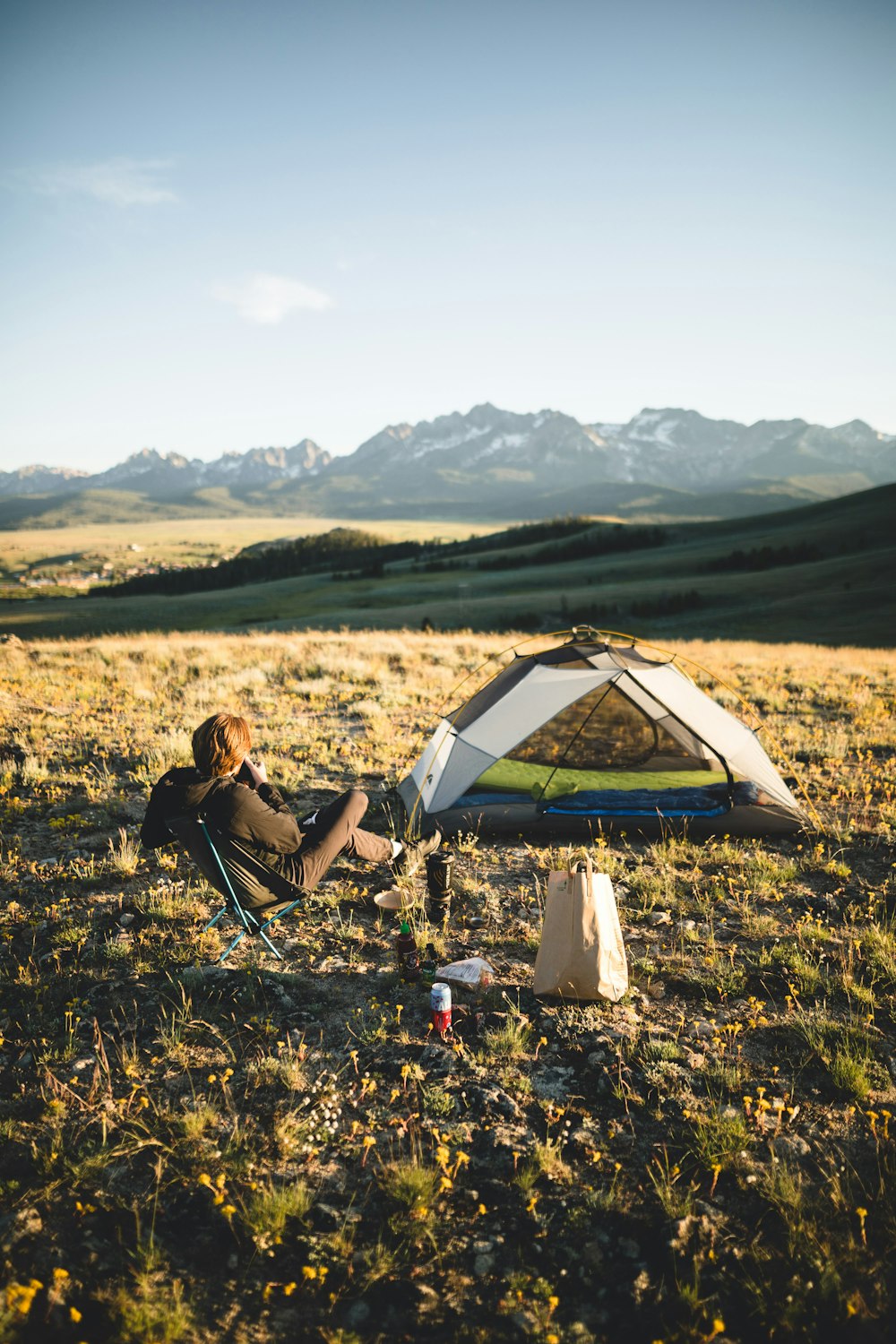 man in black jacket sitting on camping chair near tent during daytime