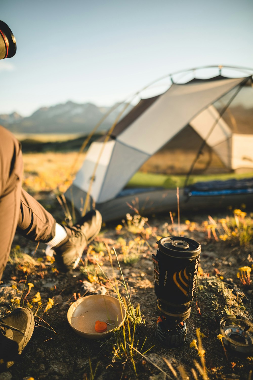 person in brown pants sitting beside white tent during daytime