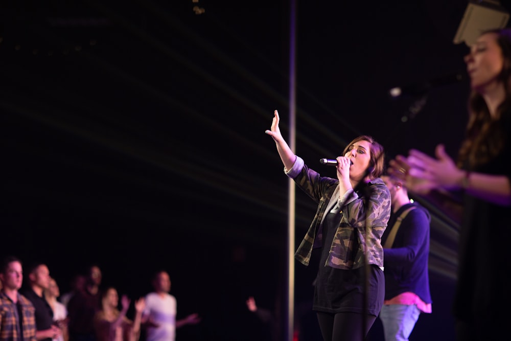 woman in black jacket singing on stage