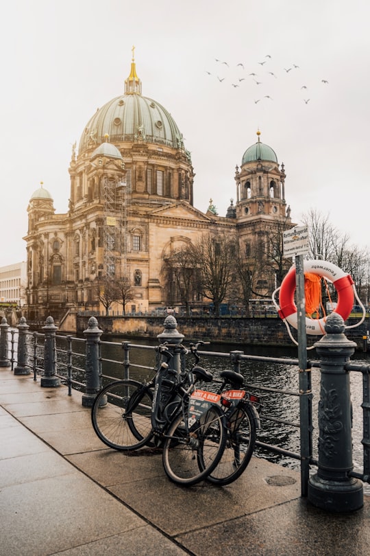 black bicycle parked beside black metal fence near brown concrete building during daytime in Berlin Cathedral Germany