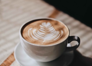 white ceramic cup with saucer on brown wooden table