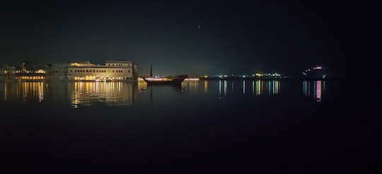 white concrete building near body of water during night time in Udaipur India
