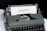 A vintage typewriter holds a sheet of white paper with the word 'EQUALITY' typed on it. The typewriter has a dark green body and black keys. The scene is set on a white and black background, giving it a minimalist yet impactful appearance.