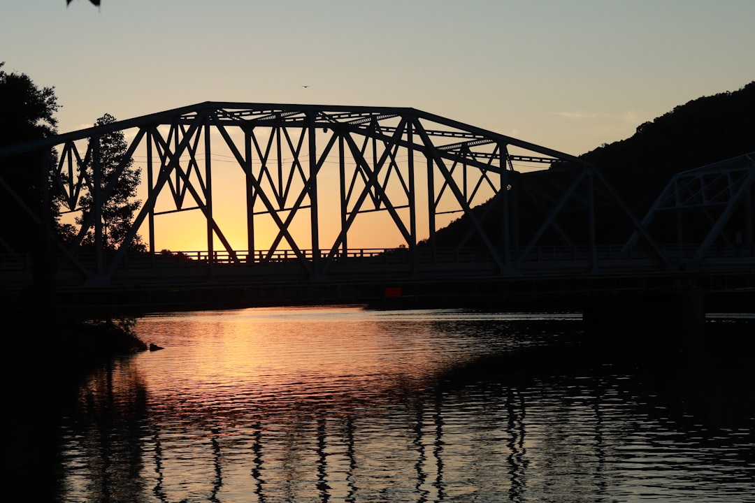 silhouette of bridge over body of water during sunset