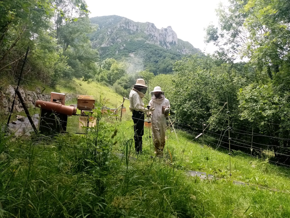 2 hommes debout sur un champ d’herbe verte pendant la journée