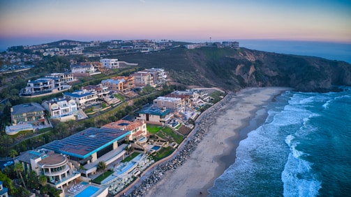 Aerial view of Santa Catarina coastline with luxury homes and natural landscape under golden sunset light.