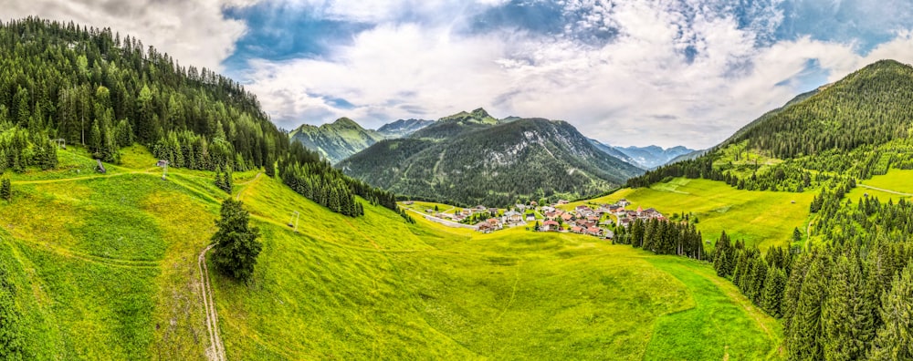 green grass field near mountain under blue sky during daytime