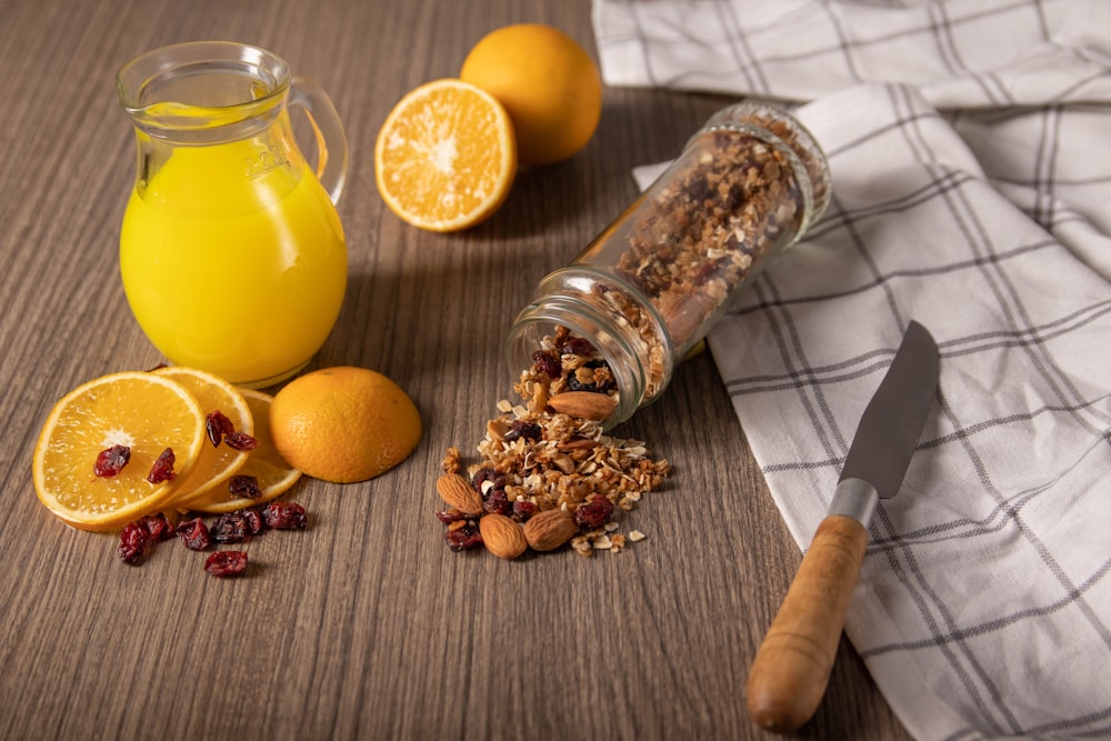 clear glass jar with yellow liquid beside sliced orange fruit