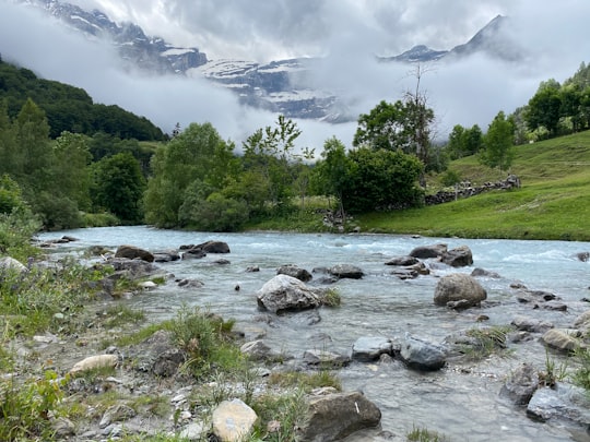 green trees near river under white clouds during daytime in Cirque de Gavarnie France