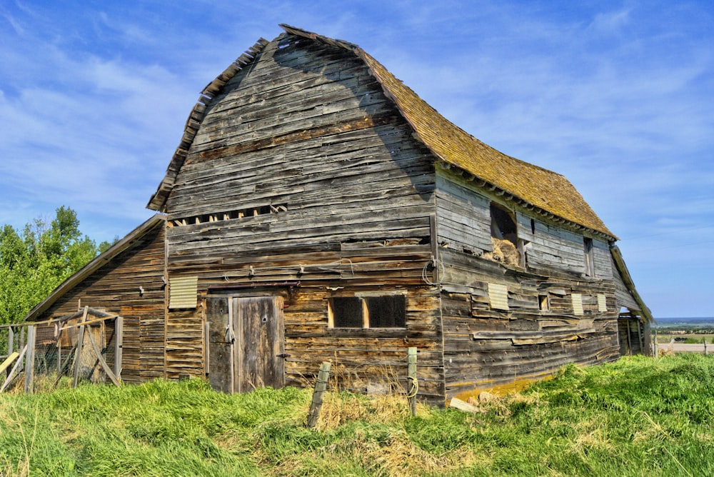 Braunes Holzscheunenhaus auf grünem Grasfeld tagsüber