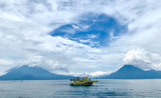 yellow boat on sea under white clouds and blue sky during daytime in Panajachel Guatemala