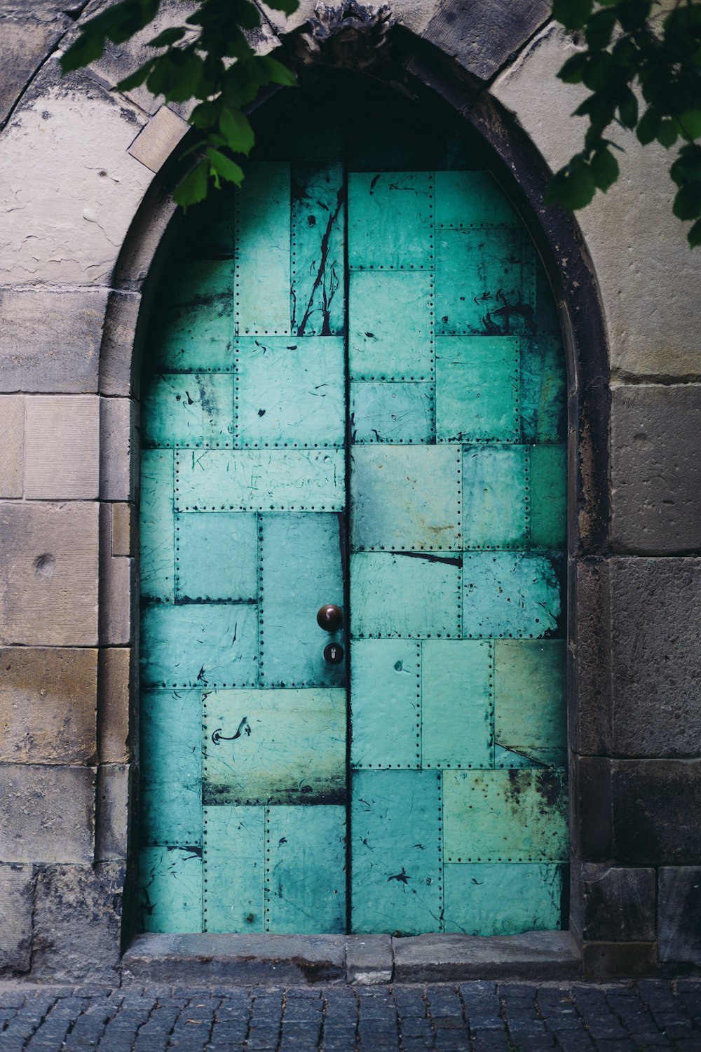 茶色のレンガの壁に緑の木製のドア