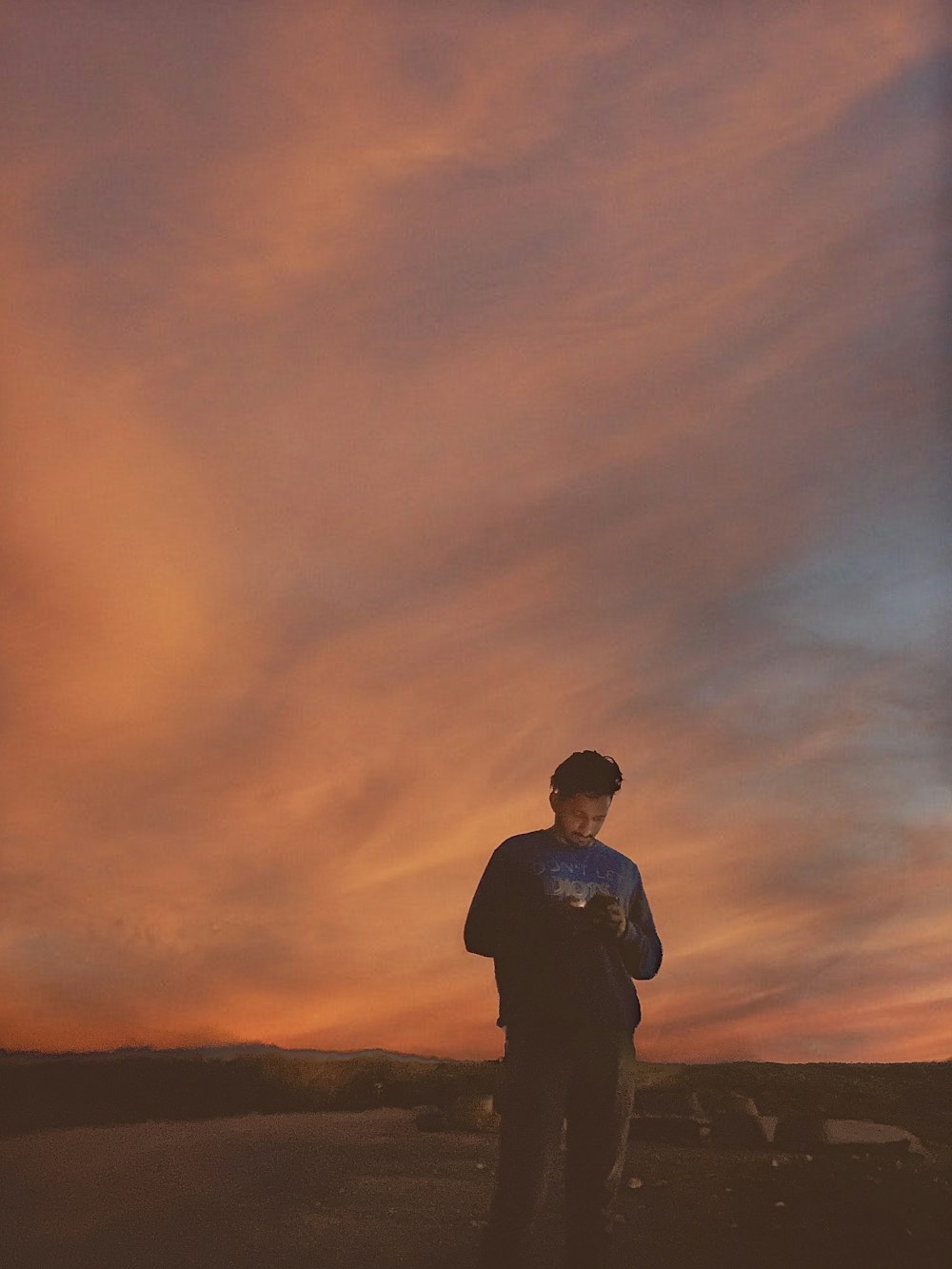 silhouette of man standing on field during sunset