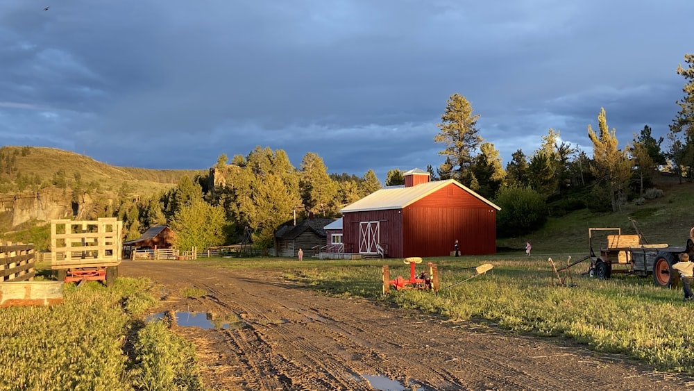 red wooden barn near green trees under white clouds during daytime